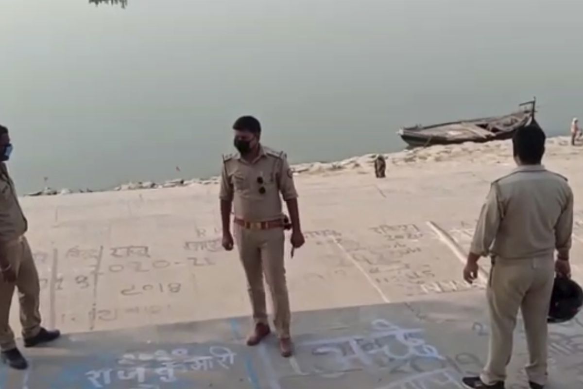 This frame grab from video provided by KK Productions shows police officials stand guard at the banks of the river where several bodies were found lying in Ghazipur district in Uttar Pradesh state India, Tuesday, May 11, 2021. 