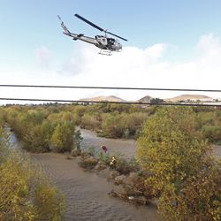 A women is hoisted out with the help of a San Bernardino County Sheriff's helicopter on Tuesday, Jan. 9, 2018, in the Santa Ana River and near the borders of Rialto, Colton, and Riverside, Calif. Three people and a dog were rescued by a helicopter after large amounts of rain fell, trapping the group at a homeless encampment in the river. (Stan Lim/Los Angeles Daily News via AP)