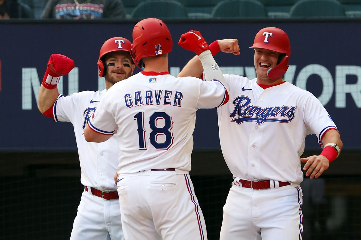 Robbie Grossman #4 and Josh Jung #6 of the Texas Rangers greet teammate Mitch Garver #18 at the plate after Garver’s three-run home run in the seventh against the Philadelphia Phillies at Globe Life Field on April 01, 2023 in Arlington, Texas.