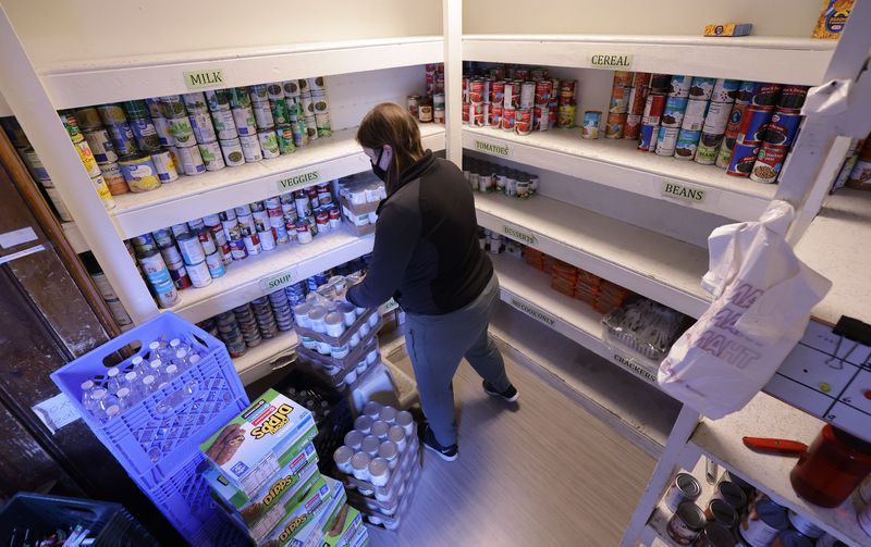 Erika Gee, Crossroads Urban Center food pantry assistant, stocks shelves at the center in Salt Lake City on Wednesday, Dec. 1, 2021.
