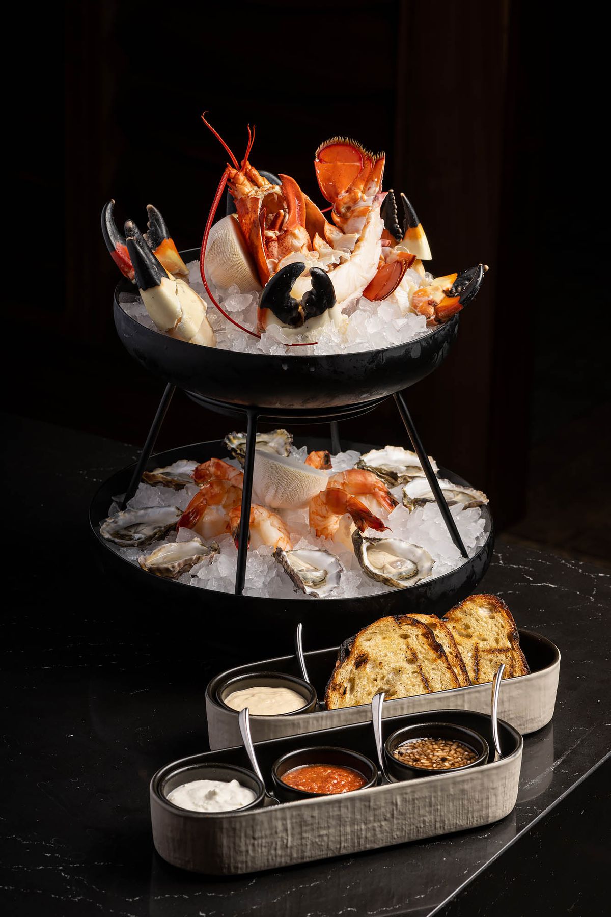 A seafood platter with oysters, shrimp, lobster, and stone crab claws at Leña in Los Angeles, California.