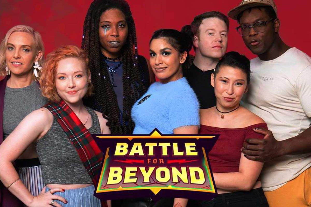 a cast stands huddles in a group looking into a camera behind a logo that says “Battle for beyond” 