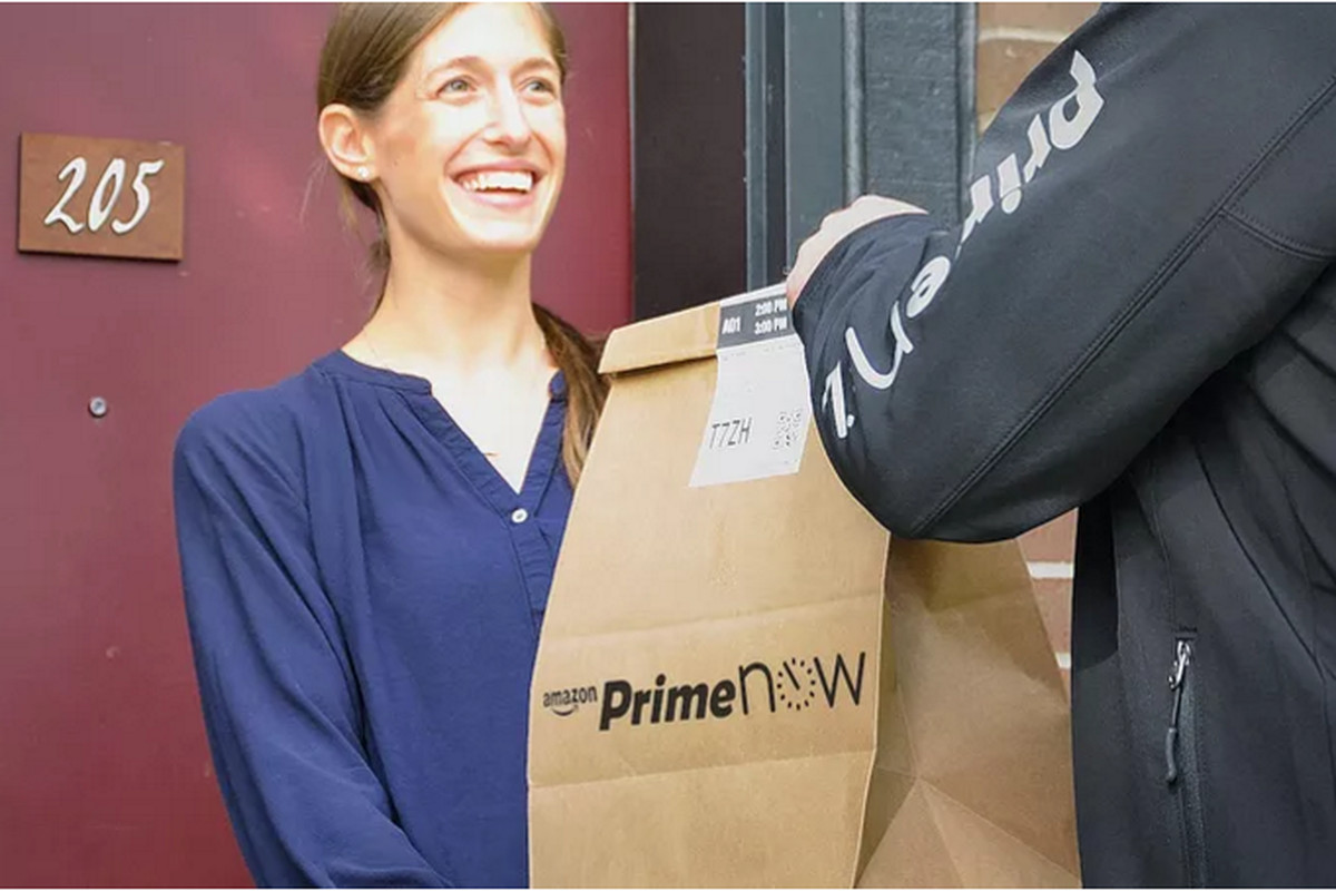 an amazon prime now delivery person hands a bag to a customer