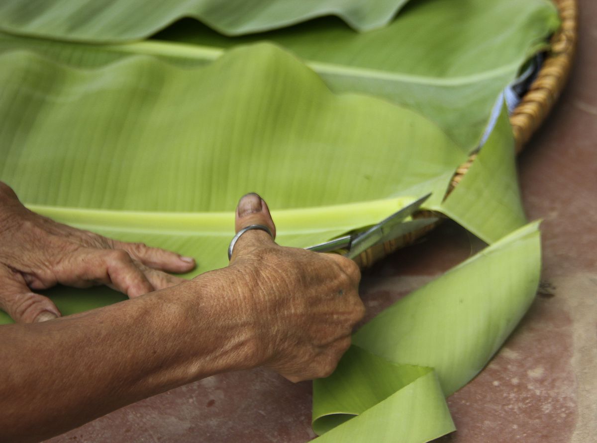 Nguyen Thi Tan, 51, cuts banana leaves into the shape of a large tray in Xuan Huong, Vietnam, on Friday, July 19, 2019.
