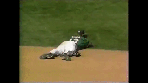 GIF of Alex Cora lying on his stomach in the field, putting his head in his mitt