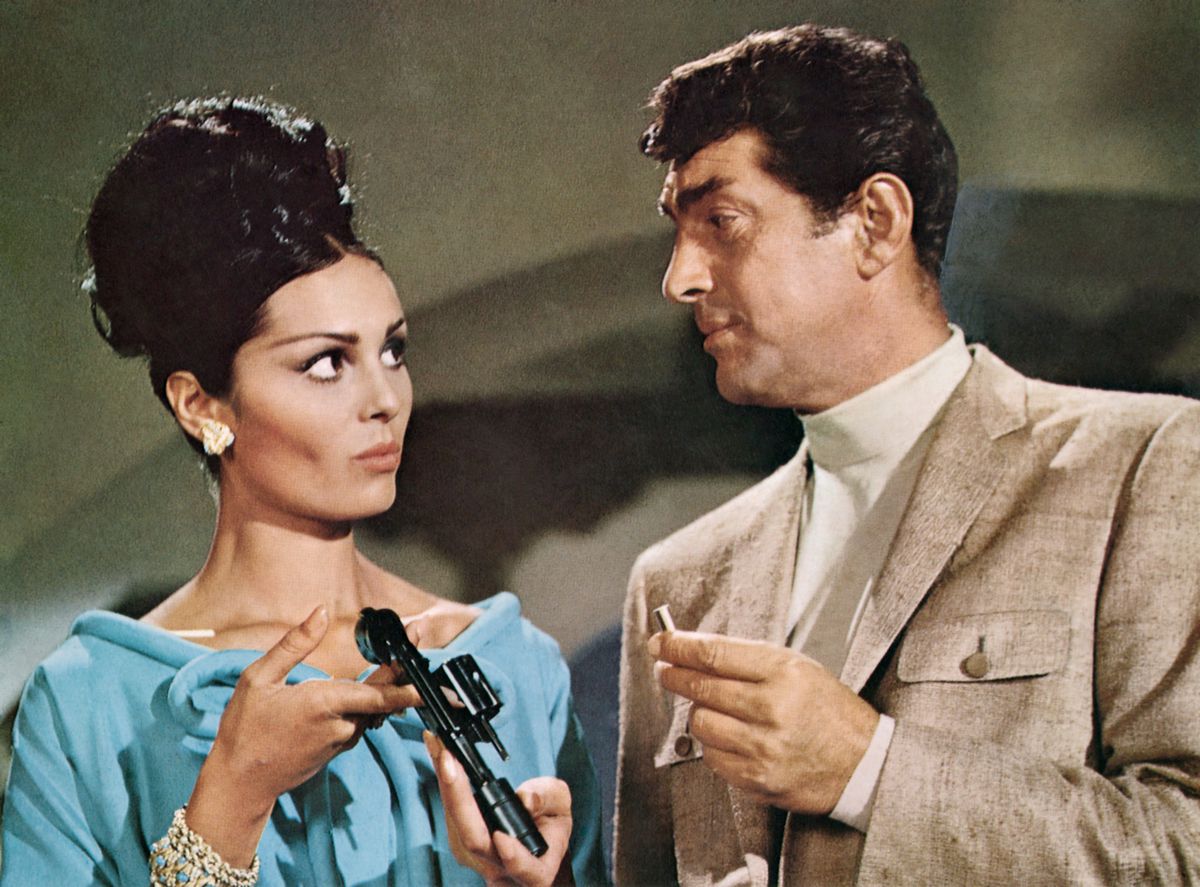 Matt Helm loads a bullet into a revolver for a black-haired woman in a blue dress
