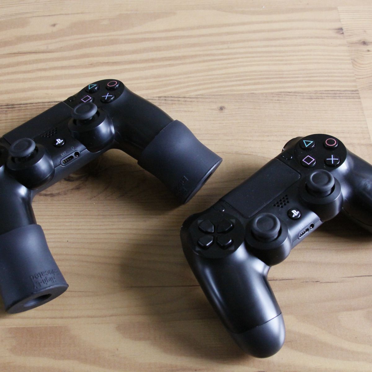 A DualShuck4 controller with Playbudz grip extenders next to a standard controller for comparison