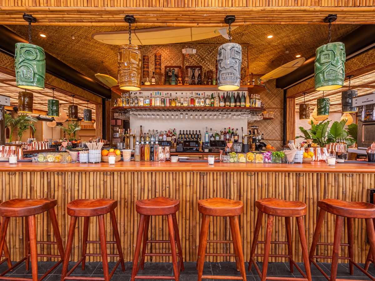 Tiki-style bar at Belles Beach House in Venice with wood chairs.