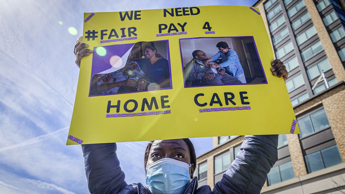 A protester hold up a sign that reads, “We need fair pay for home care.”