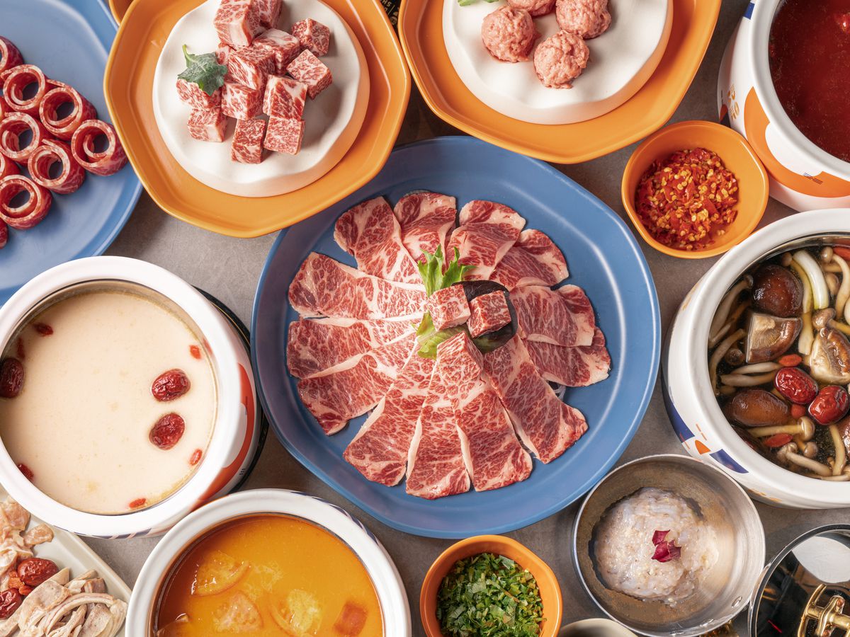 A hot pot spread at the Dolar Shop full of meats and broths.