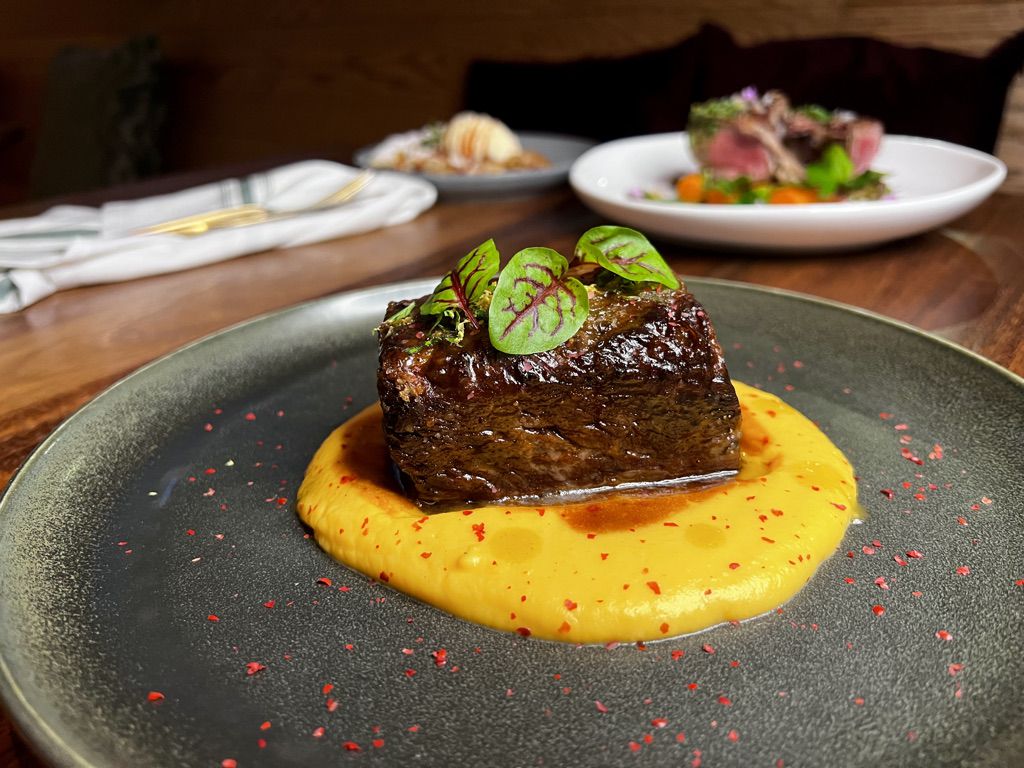 Beef short ribs in a yellow sauce on a plate. 