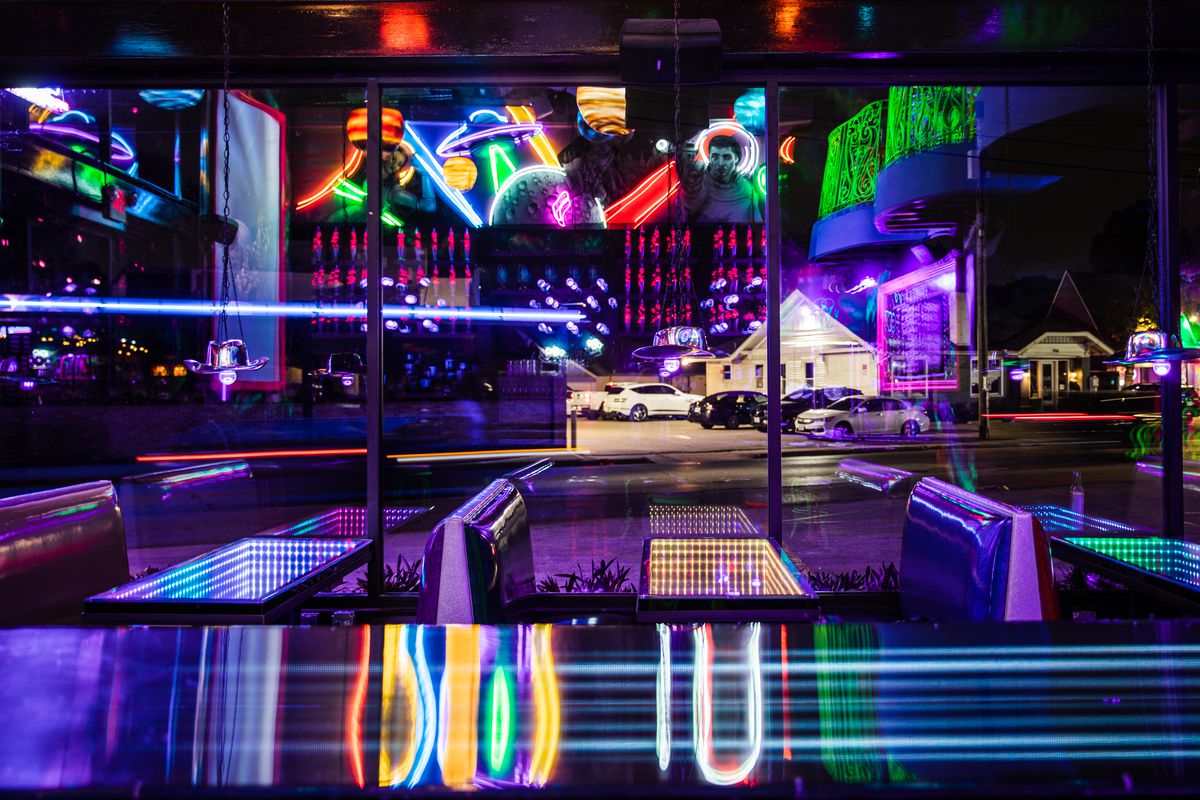 The lounge area at Roswell’s Saloon with neon lights, projection mapping, and views of the outside world.