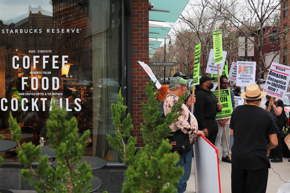 People hold signs while protesting in front of a Starbucks store on April 14, 2022 in New York City.