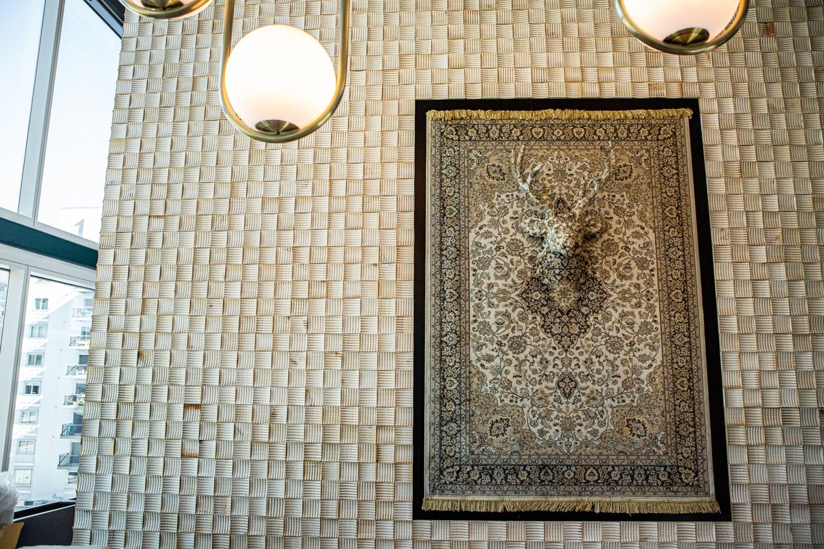 A wall with glass panels and a rug artwork with a deer head underneath it.