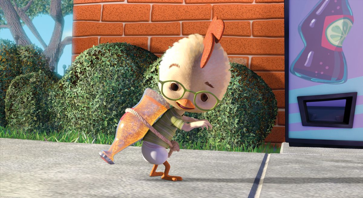 An animated chick with a huge head and green glasses straps a bubbly bottle of soda to his back while standing outdoors by a brick building in Disney’s 2005 animated CG movie Chicken Little