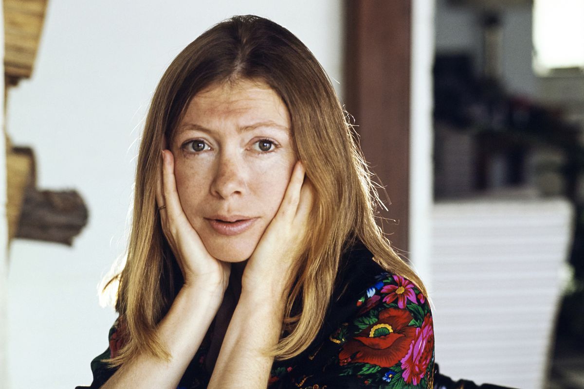 A portrait of Didion with her hands cradling her face.