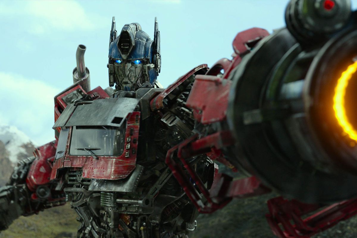Optimus Prime (Peter Cullen) aiming an arm-mounted energy cannon in Transformers: Rise of the Beasts.