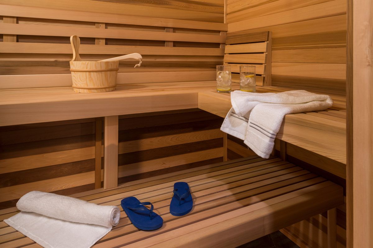 The inside of a home sauna with towels and flip flops on the benches.