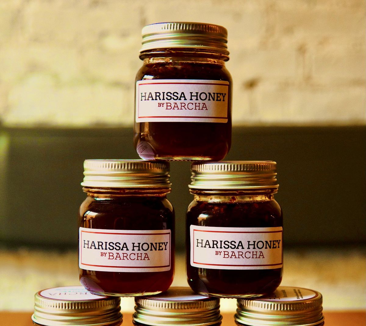 Gold-lidded jars of Barcha’s harissa hot honey stacked on top of each other.