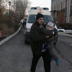 A man carries a child after shelling between Russian-backed separatists and Ukrainian government forces in a residential area of the town of Artemivsk, Ukraine, Friday, Feb. 13, 2015. Despite a looming cease-fire deal for eastern Ukraine, a government-held town 40 kilometers (25 miles) behind the front line has been hit by shelling, killing at least one person. The deadline for the warring sides to halt hostilities is Sunday morning at one minute after midnight. 