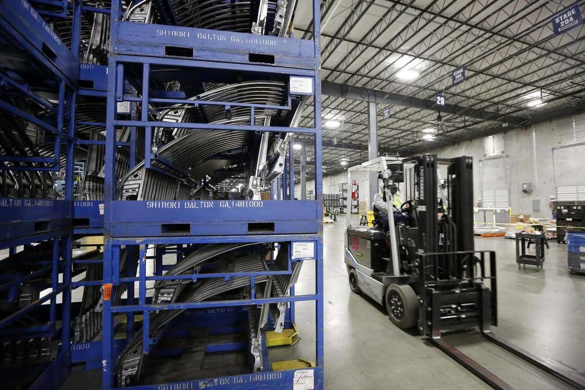 In this Dec. 12, 2014 file photograph, a worker drives an electric forklift past a stack of window frames at Nissan's 1.5-million-square-foot integrated logistics center in Canton, Miss. The Commerce Department reports on business stockpiles in December o