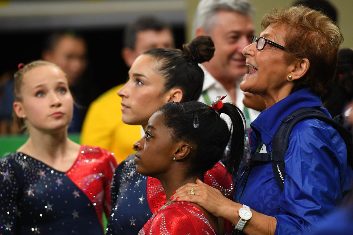 Martha Karolyi stands with Simone Biles and Team USA gymnasts.