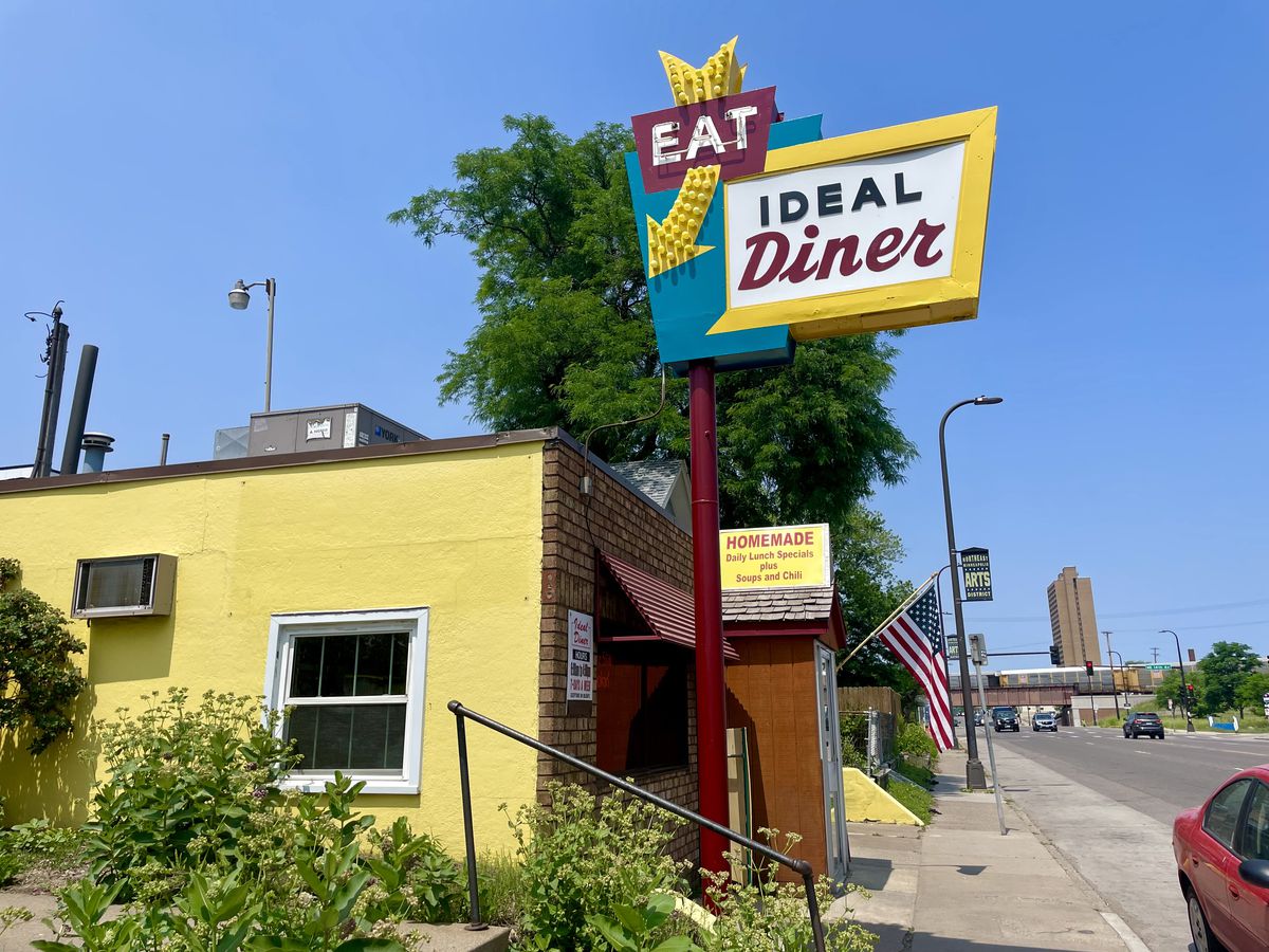 A yellow building with a sign that says “Eat Ideal Diner” against a blue sky.