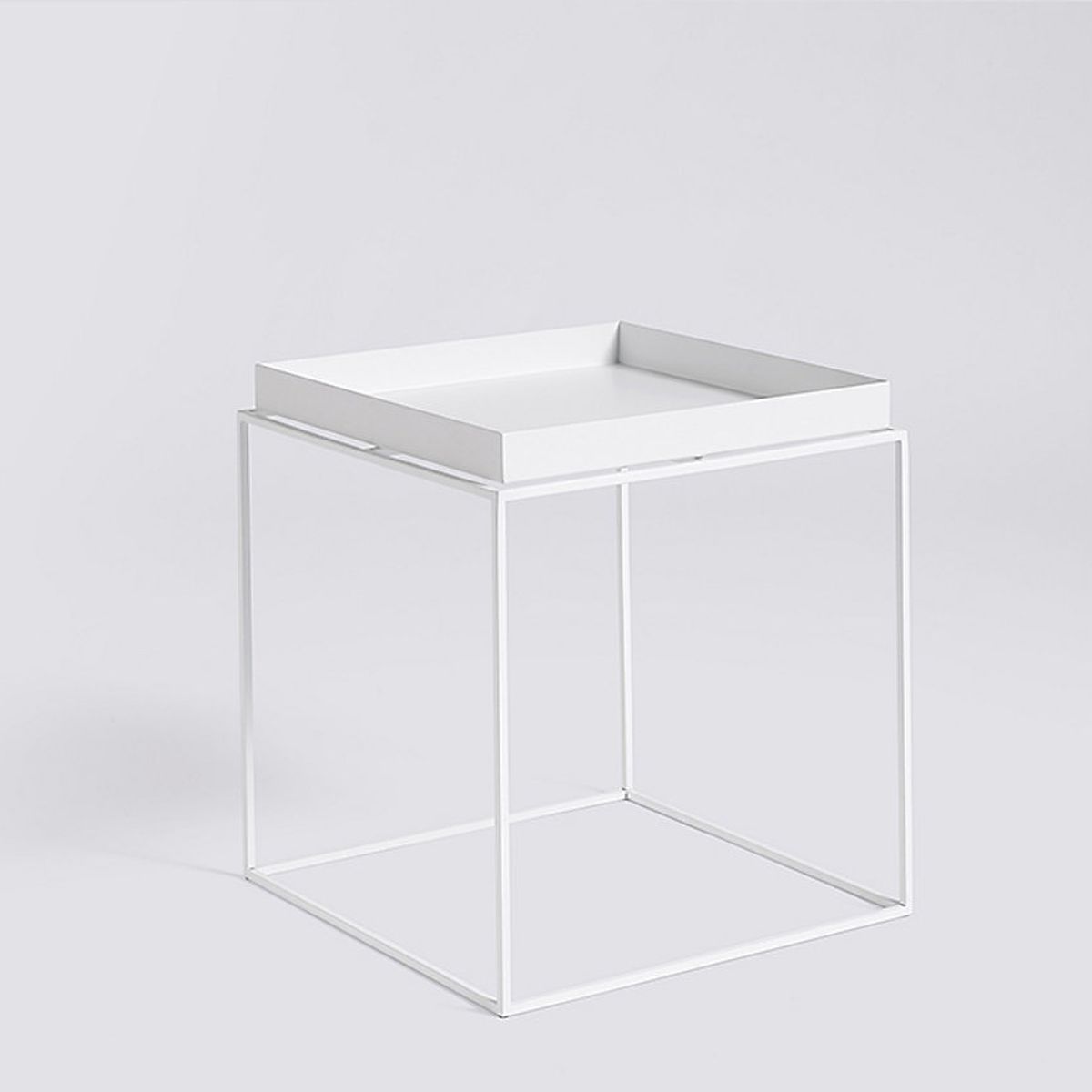 A all-white nightstand that features a tray top and four legs. 