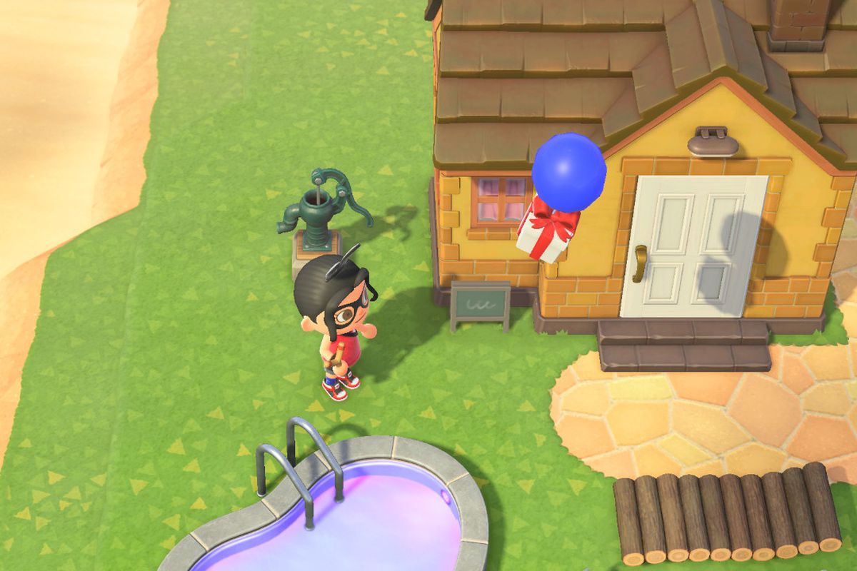 An Animal Crossing character holding a slingshot stands under a blue balloon with a gift attached