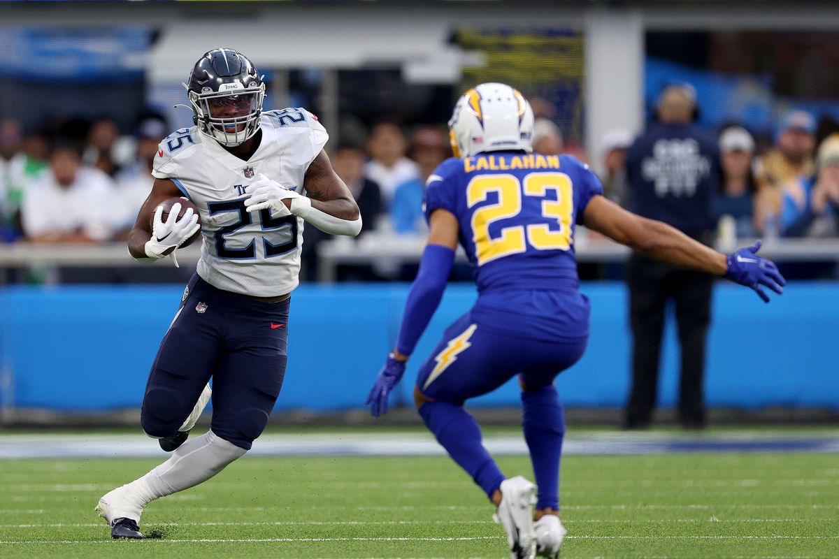 Hassan Haskins #25 of the Tennessee Titans runs with the ball in front of Bryce Callahan #23 of the Los Angeles ChargBryce Callahan #23 of the Los Angeles Chargersduring a 17-14 loss to the Chargers at SoFi Stadium on December 18, 2022 in Inglewood, California.