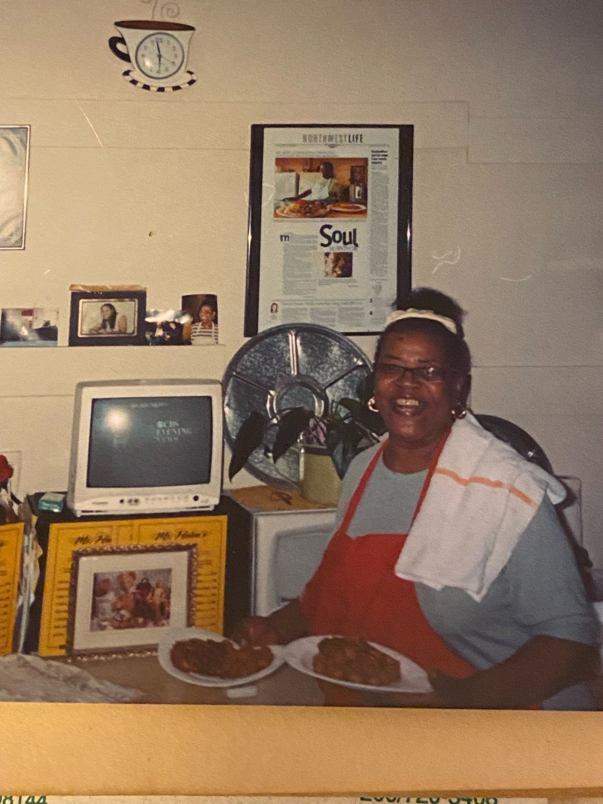 A woman stands holding two plates of food in a diner.