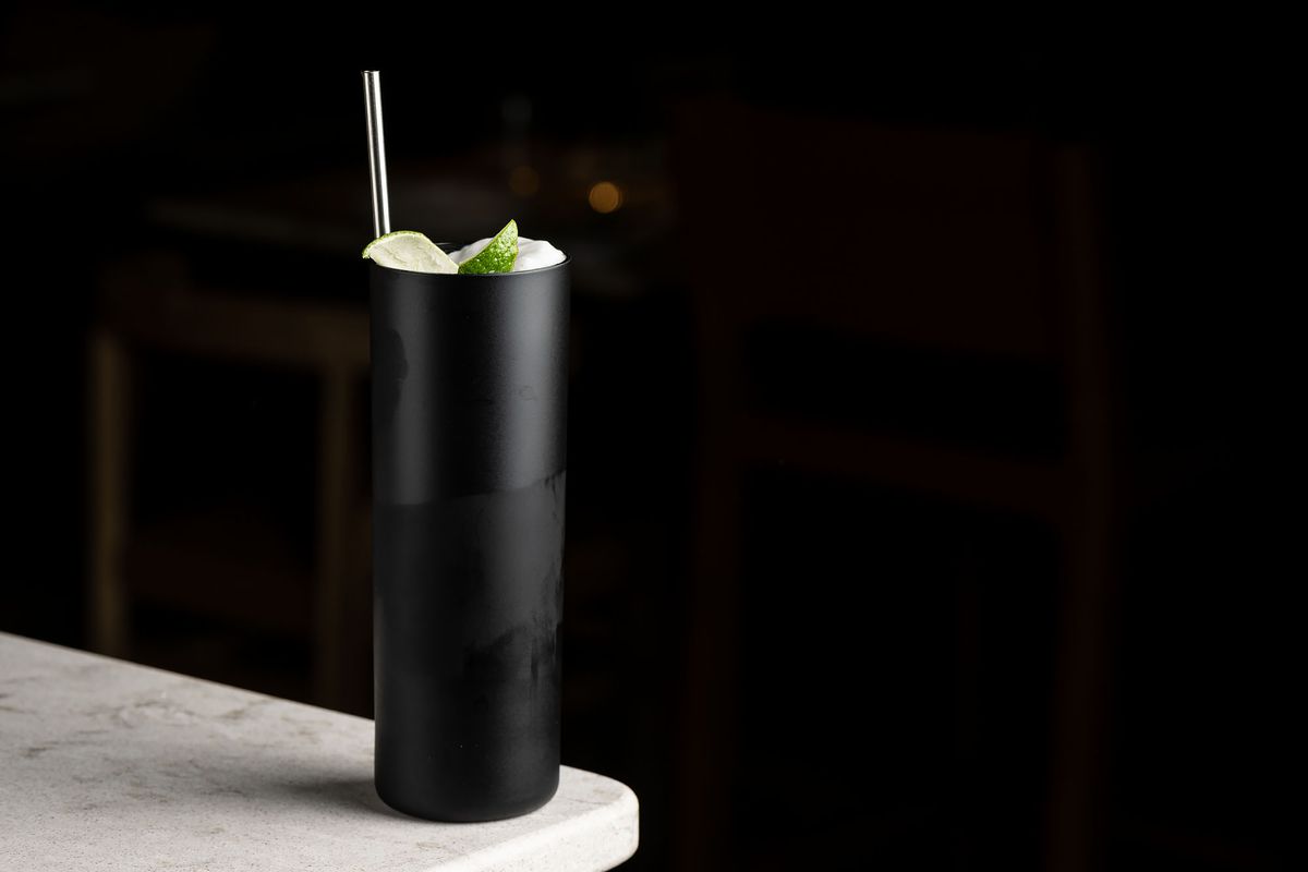 A moody cocktail in all black glass against a black background.