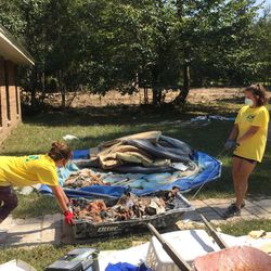 Mady Pomeroy, 20, of Zachary, Louisiana, and her sister, Sydney, 12, use an ice sled to remove debris from a flooded-out home in Lumberton, Texas, on Saturday, Sept. 9, 2017.