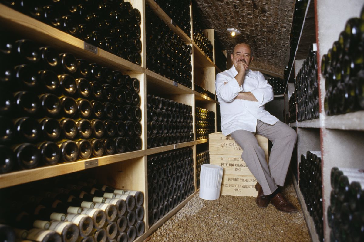 Man sitting on a crate inside a wine cellar.