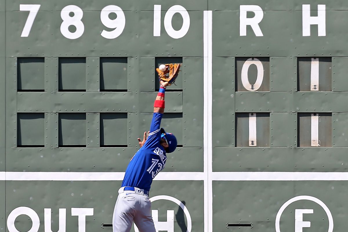 Lourdes Gurriel Jr. #13 of the Toronto Blue Jays catches Hunter Renfroe #10 of the Boston Red Sox fly out during the first inning of the MLB game at Fenway Park on July 28, 2021