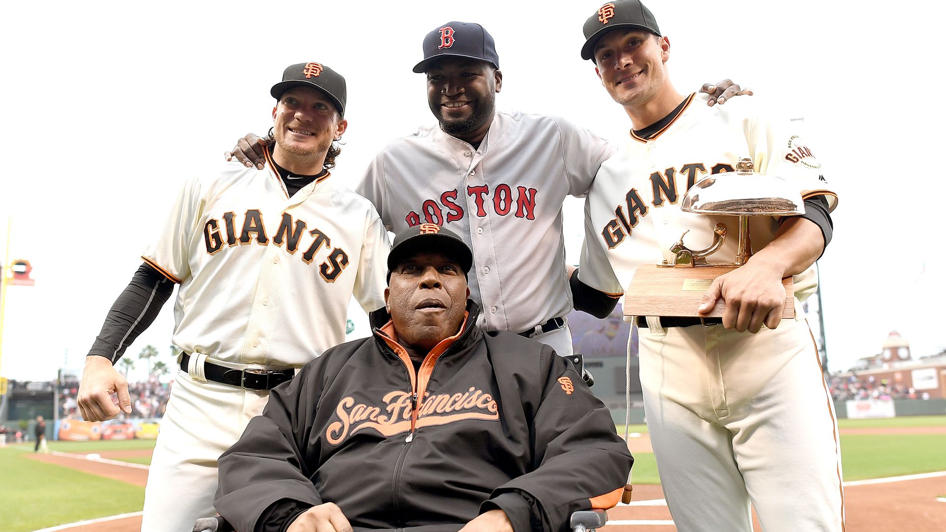 Willie McCovey, in a wheelchair, posing with Jake Peavy, Javier Lopez, and David Ortiz