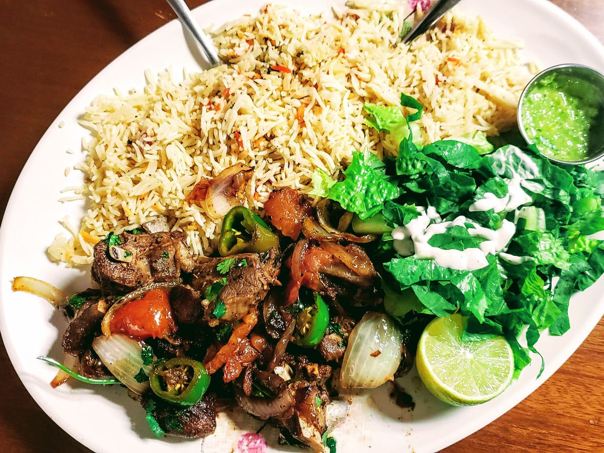 A plate of Somalian food with rice, meat, and a side salad at Banadir Somali Restaurant.