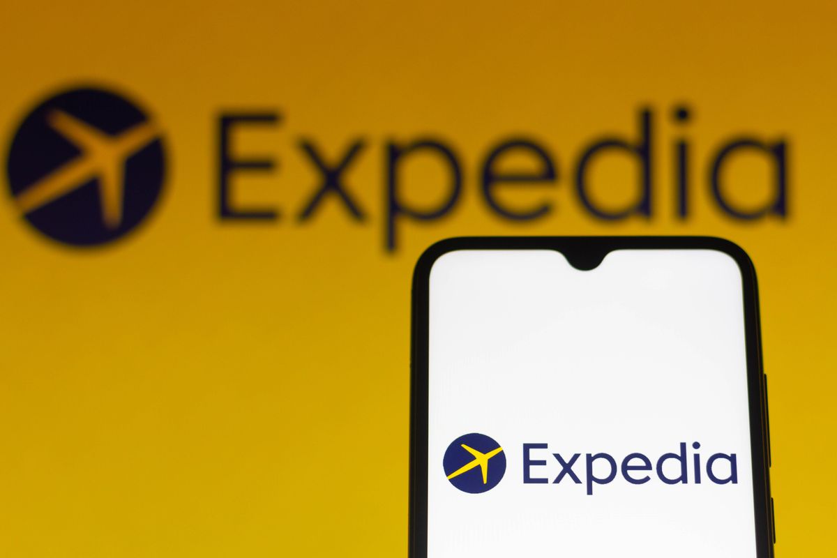In this photo illustration, the Expedia logo seen displayed...