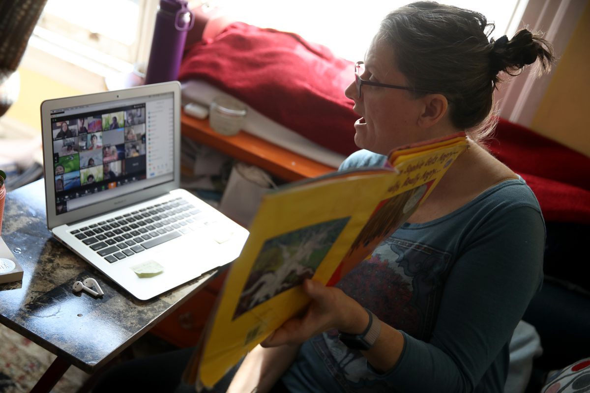 A teacher holds up a book teaching her students online.