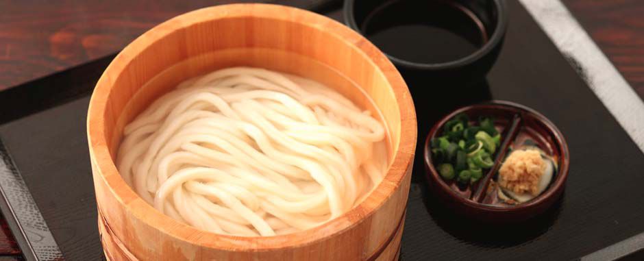 Noodles in soup in a deep wooden bowl.