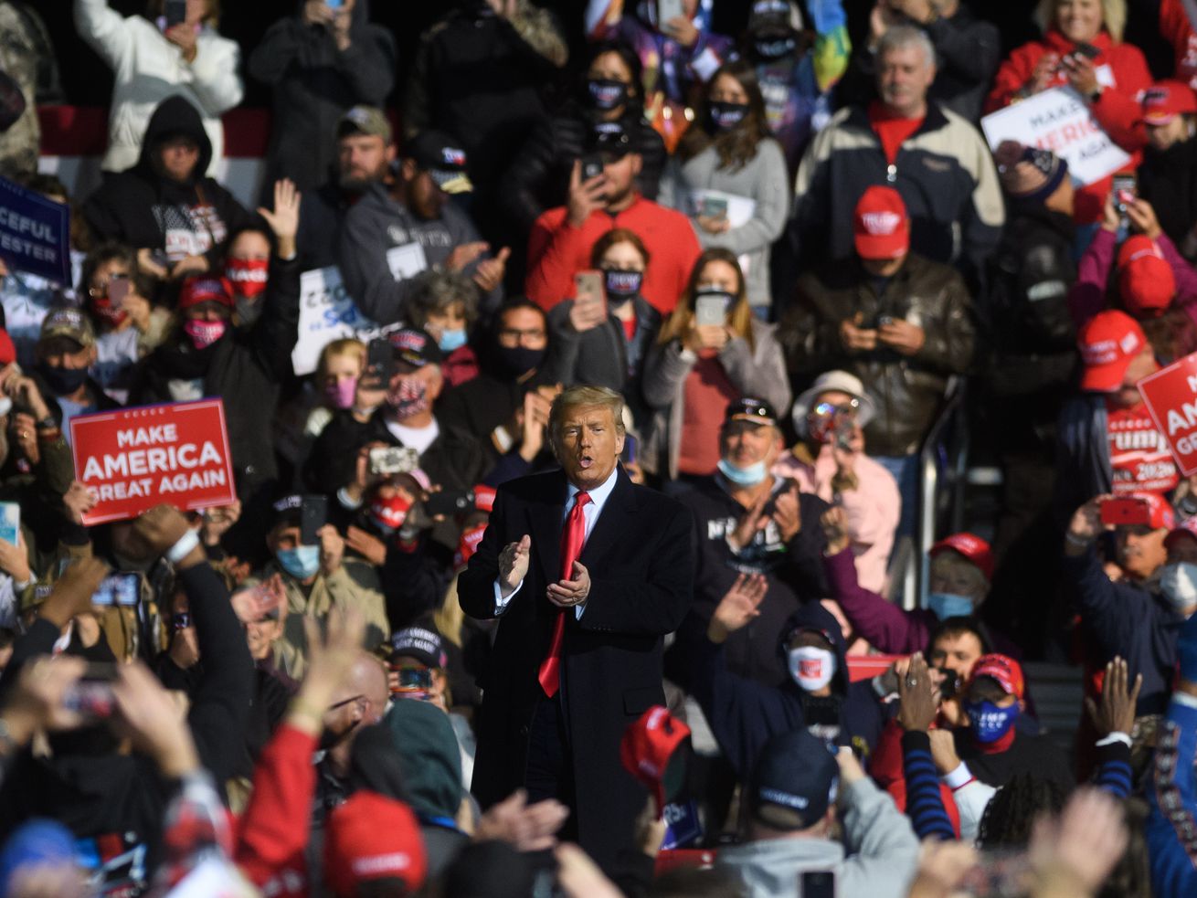 Trump, not wearing a face mask, standing in the middle of a crowd at a campaign rally.