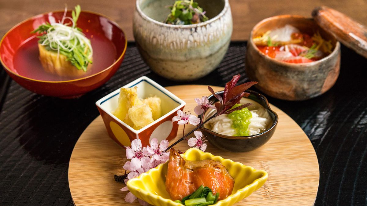 Several plates of food in ceramic and lacquered plates, with plenty of sashimi.