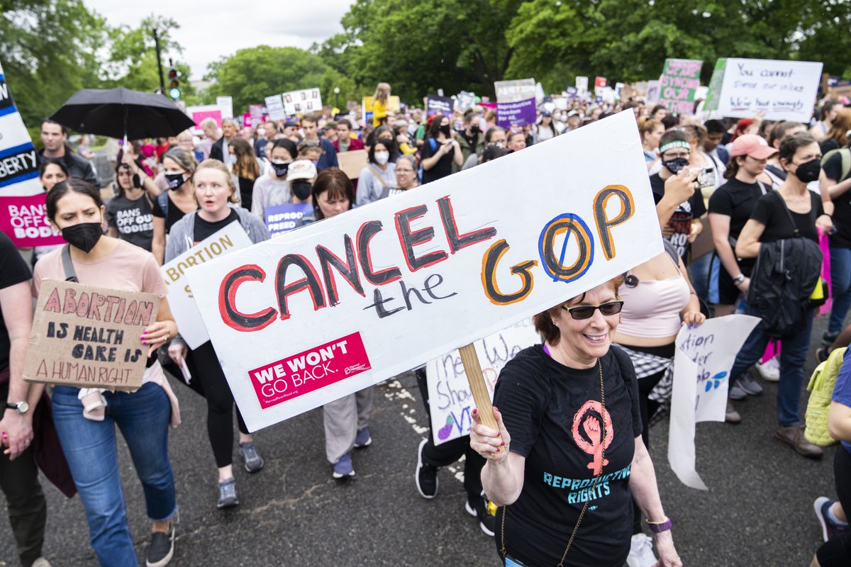 A protester in a crowd carries a sign that reads, “Cancel the G.O.P.”