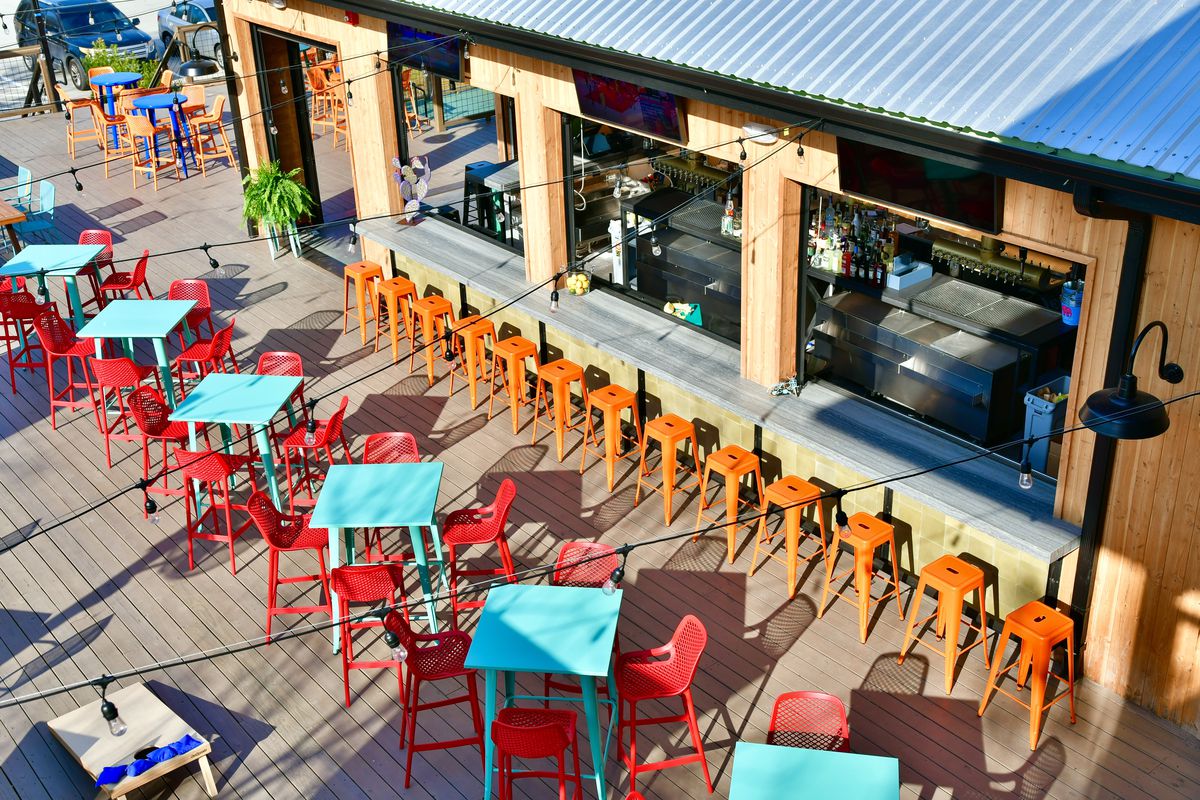 Patterson Park’s patio with multiple chairs, tables, and an indoor bar that extends outdoors.