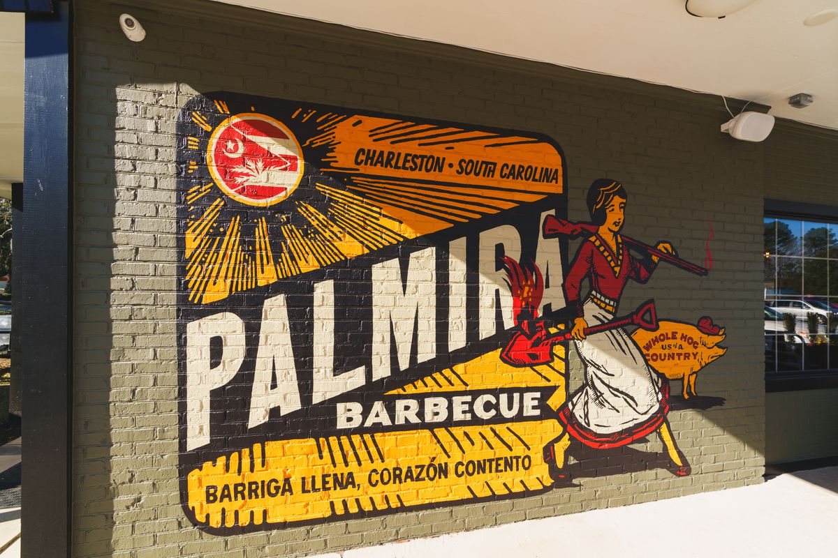 A yellow wall reading “Palmira Barbecue” with a woman carrying a flaming shovel.
