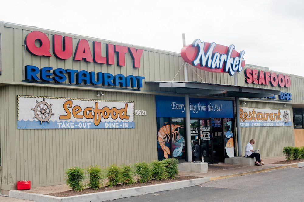 The front of a restaurant and market with the sign “Quality Restaurant” and “market” and “Seafood”.