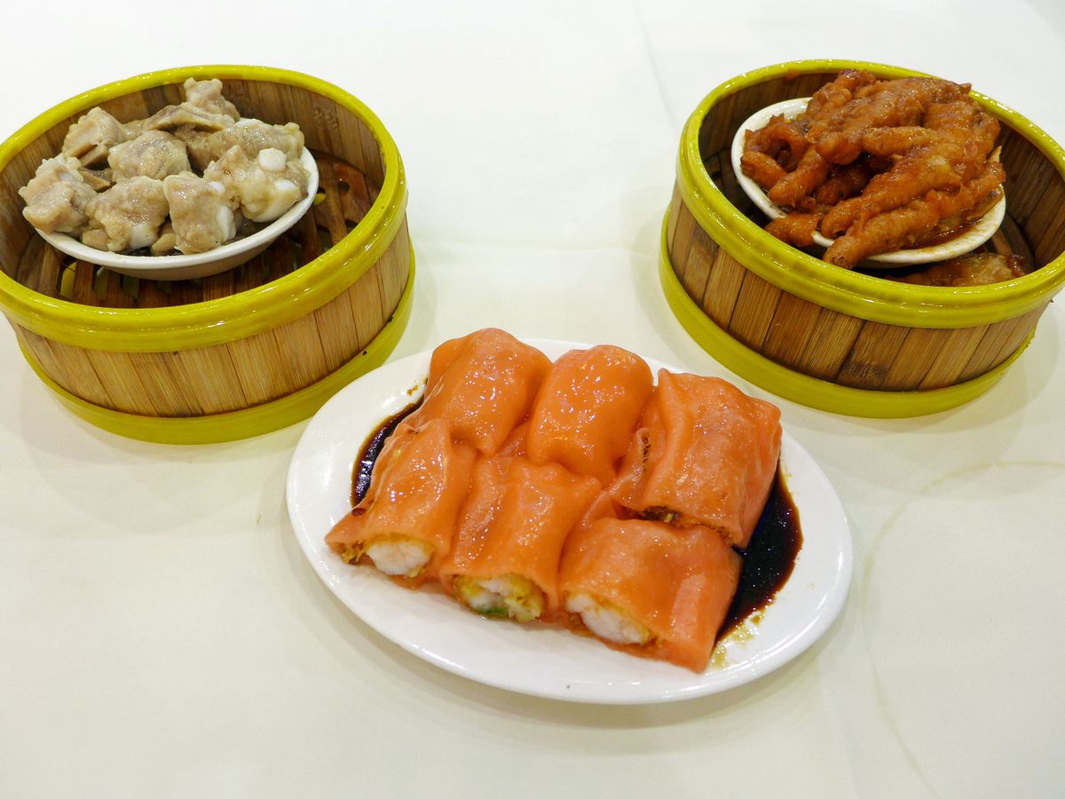 Three steamers of chicken feet, riblets, and orange rolls cut in segments.