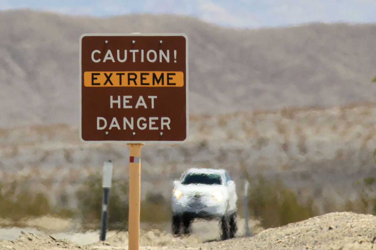 DEATH VALLEY NATIONAL PARK, CA JULY 14: Heat waves rise near a heat danger warning sign on the eve of the AdventurCORPS Badwater 135 ultra-marathon race on July 14, 2013 in Death Valley National Park, California.