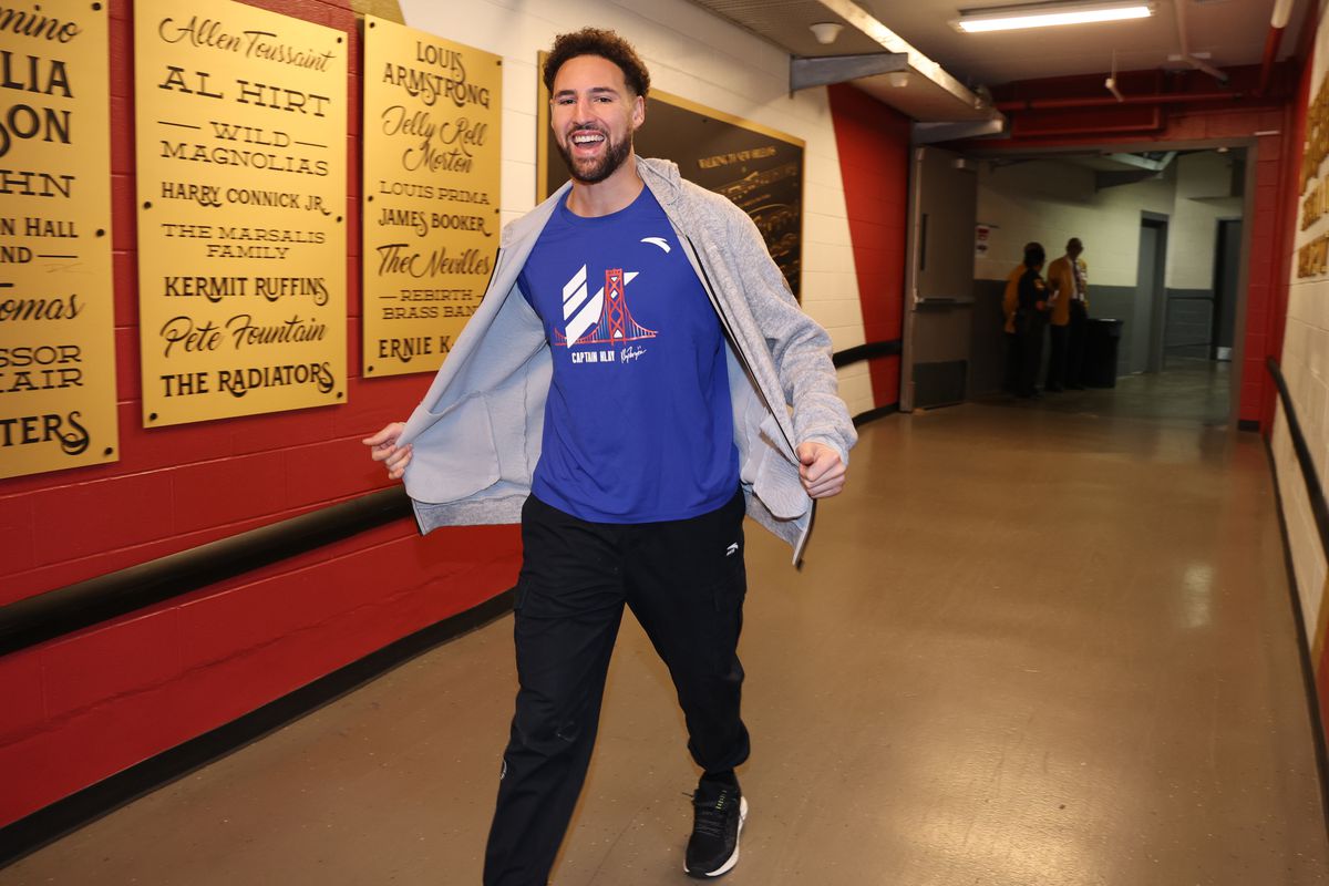 Klay Thompson smiling while walking into an arena. 