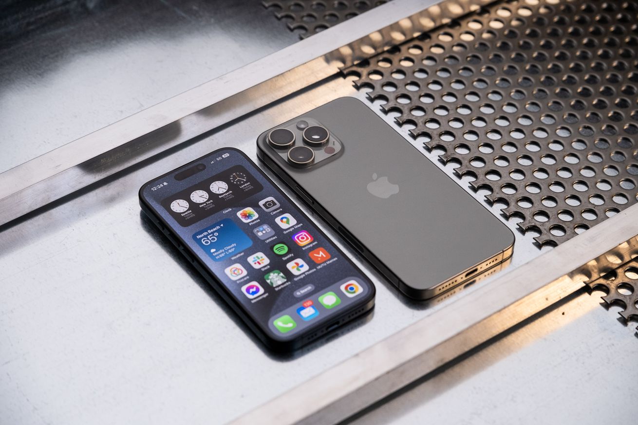 An iPhone 15 Pro and Pro Max side-by-side on a metal surface.